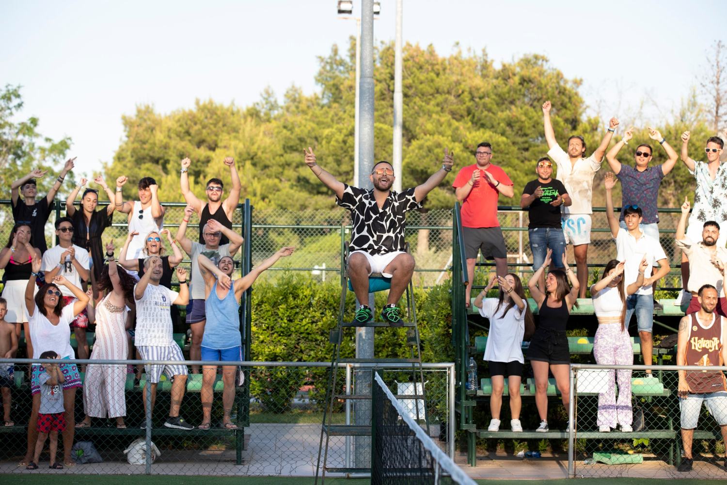L'uomo sul seggiolone con le braccia alzate davanti a una tribuna gremita e in festa