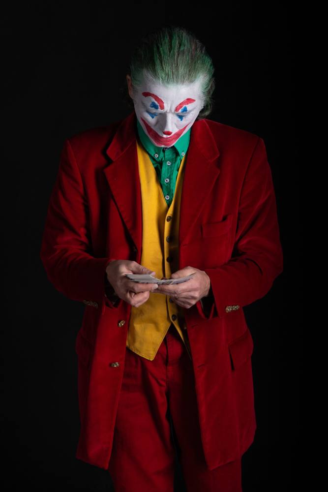 Joker a testa china che mescola un mazzo di carte, su fondo nero